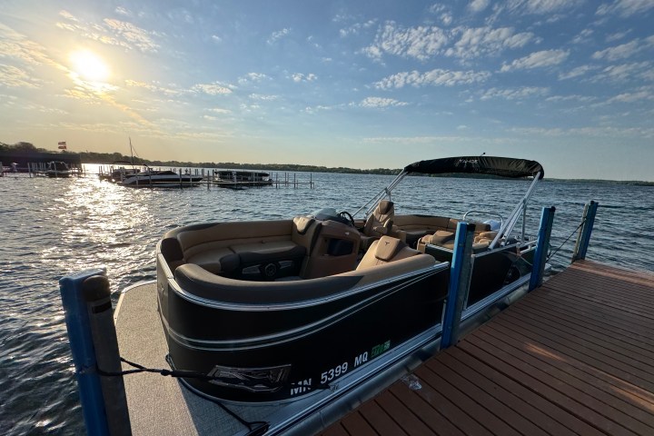 Pontoon boat docked on a lake at sunset with a clear sky.