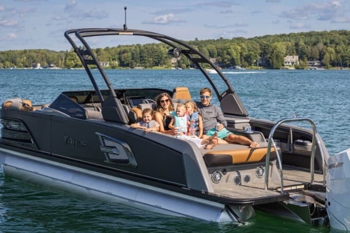 Family sitting on a motorboat on a lake with trees in the background.